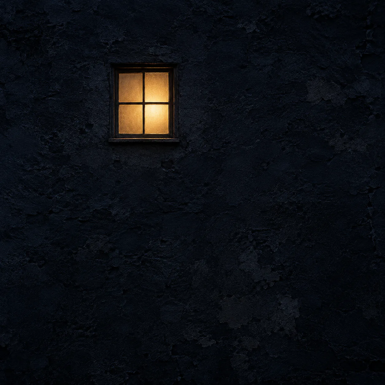 One small amber-lit window, slightly left of centre in the upper third of an old navy-black wall at night.
